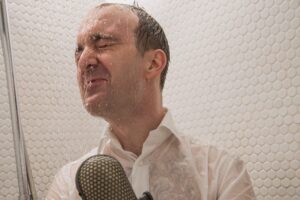 Ein Mann in der Dusche mit einem Mikrofon