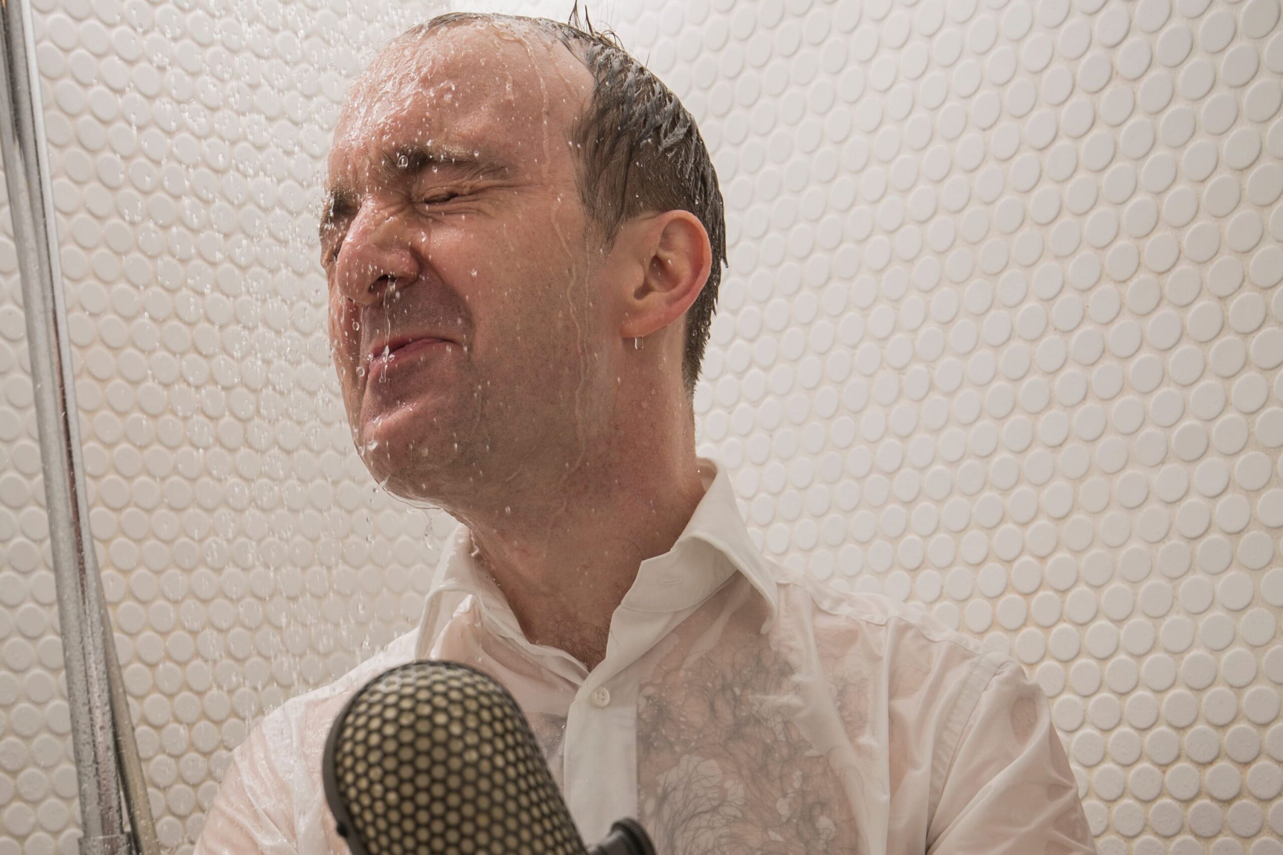 Ein Mann in der Dusche mit einem Mikrofon